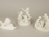 three white figurines of people and animals on a white surface