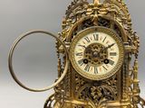 a gold clock with a magnifying glass in front of it