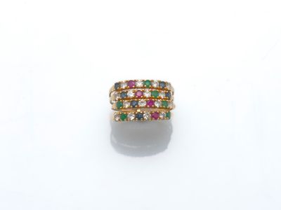 une bague en or ornée de pierres multicolores sur un fond blanc