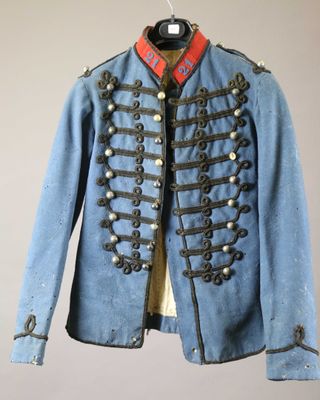 an old blue military jacket hanging on a hanger on a wall