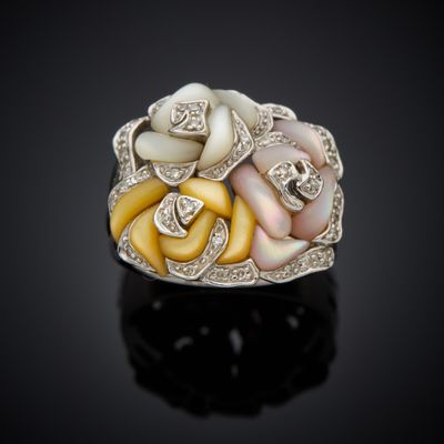 a close up of a white and yellow flower ring on a black surface