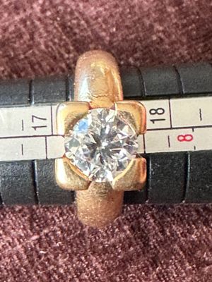 une bague en or sertie d'un diamant posée sur une règle