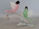 two glass birds sitting on top of a glass branch