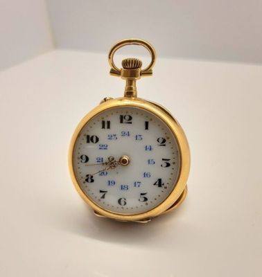 une montre de poche en or sur une surface blanche