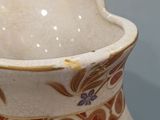 a white vase with a floral design on it