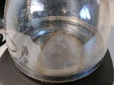 a glass tea pot sitting on top of a black coffee maker