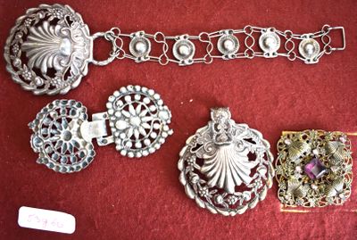 a lot of silver bracelets and brooches on a red cloth