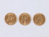 trois pièces d'or sont alignées sur une surface blanche