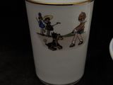 a cup with a picture of people on it next to a plate