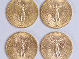 four gold coins with a statue on them sitting on a white surface