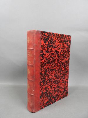 un livre rouge et noir posé sur une surface blanche