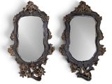 On voit deux miroirs aux motifs ouvragés sur fond blanc