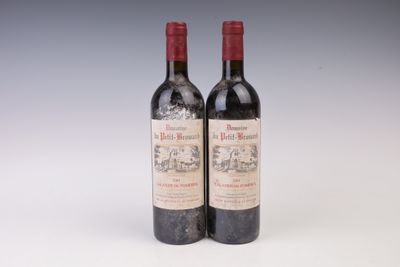 two bottles of red wine sitting next to each other on a white surface