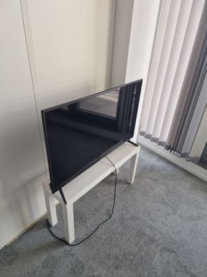 un téléviseur à écran plat posé sur un support dans le coin d'une pièce
