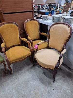 four chairs are lined up in a room with a table and a lamp