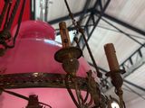 un lustre avec une lampe rose suspendue au plafond