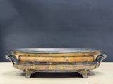 an old brass bowl on a wooden table with a black background