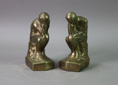 pair of bronze figurines of a man and a woman sitting on a rock