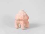a small pink figurine sitting on a white surface