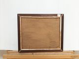 an old picture frame sitting on top of a wooden shelf next to a white wall