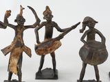 three bronze figurines of a man and a woman playing musical instruments