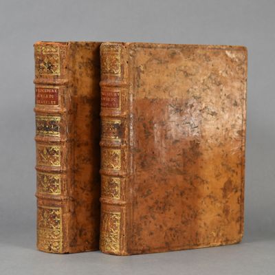 two old books are sitting on top of each other on a table