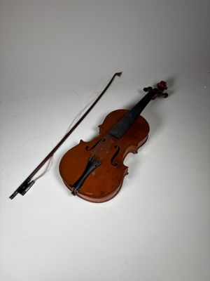 un vieux violon avec un archet et une repose-archet posé sur une surface blanche