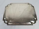 an old silver plate with a handle on a white surface