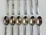 six silver spoons are arranged in a row on a white surface