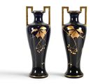 une paire de vases noirs et dorés ornés de feuilles sur fond blanc