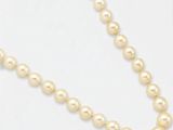gros plan d'un collier de perles sur une surface blanche