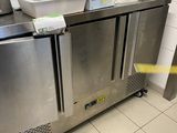 un plan de travail en acier inoxydable dans une cuisine professionnelle, avec une poubelle