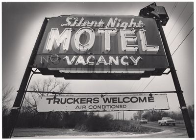 photographie en noir et blanc d'une enseigne de motel avec un camion en arrière-plan