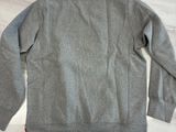 un sweat-shirt gris posé sur une table, à côté d'une paire de chaussures