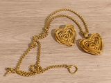 gold plated heart necklace and earring set on a wooden table