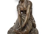 statue en bronze représentant une femme assise sur un socle, les mains posées sur les genoux