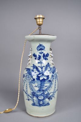un vase bleu et blanc avec une anse dorée sur fond gris