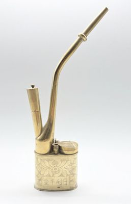 un vieux porte-pipe en laiton d'où sort une pipe