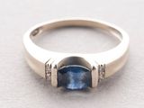 a close up of a ring with a blue sapphire and diamonds