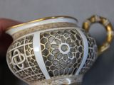 a white and gold tea pot with a gold handle