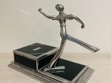 statue of a woman holding a tennis racquet on top of a wooden table