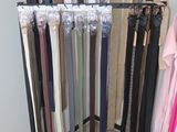 a lot of belts hanging on a rack in a room