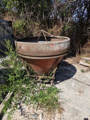 a rusted pot sitting on the ground next to a car