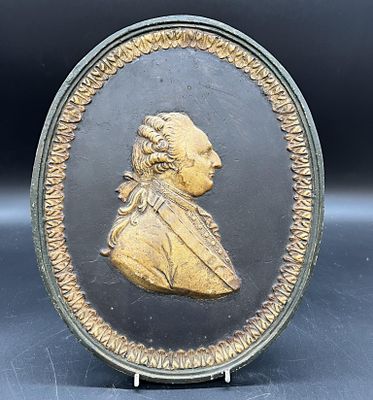 une image représentant une plaque dorée et noire sur laquelle figure le profil d'un homme