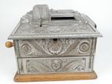 an antique silver metal money box with a wooden base
