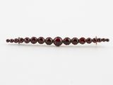 a close up of a bracelet with garnets on a white surface