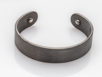 gros plan d'un bracelet métallique sur une surface blanche