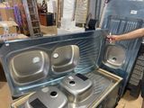 a man standing next to a metal stove with three pans inside of it