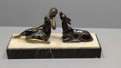 deux statues en bronze représentant une femme et un chien, posées sur un socle en marbre
