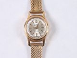 a gold wrist watch with a white face on a white surface